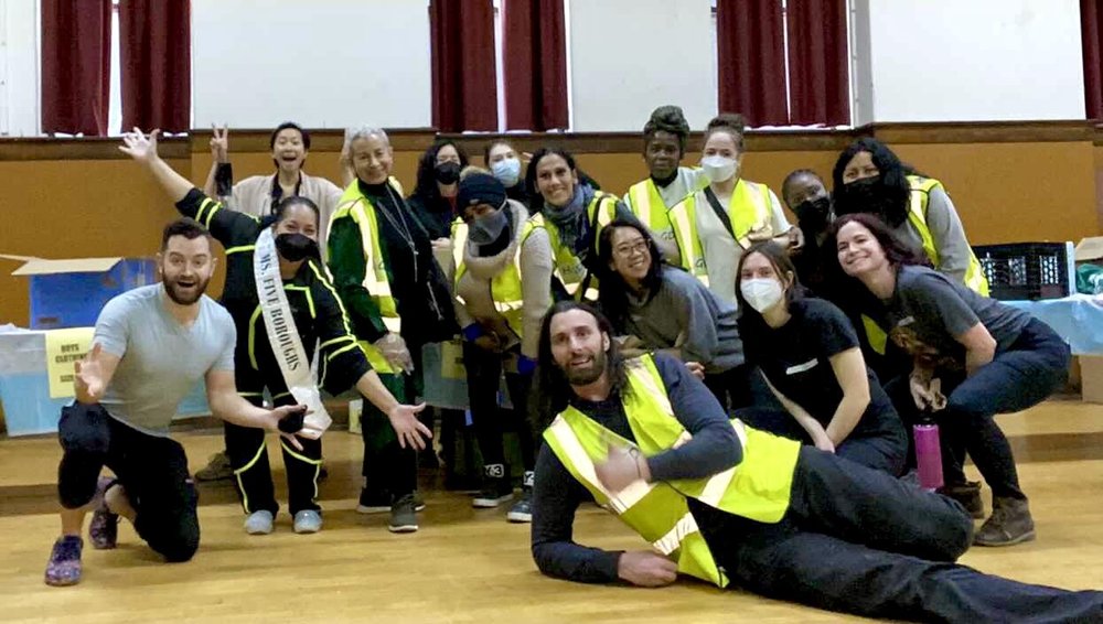 Group of House of Good Deeds volunteers in bright vests smiling and posing at a community event for the House of Good Deeds, promoting charitable initiatives and support for entrepreneurial success.